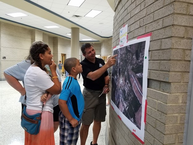 A community partner from Camden County shows families a walk and bike route map at a school open house.