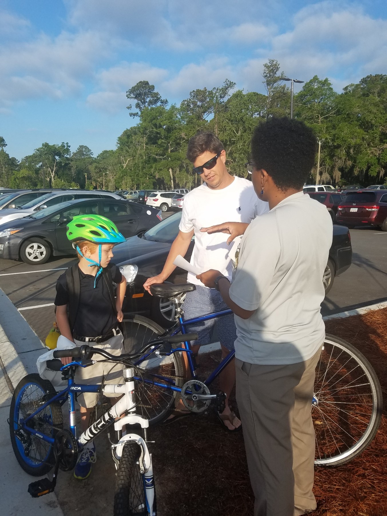 Parent and child learn about bicycle safety and receive materials from a SRTS volunteer while they stand beside bicycles.
