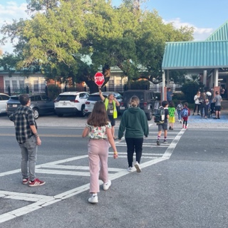 cross walk in front of school with families crossing and crossing guard
